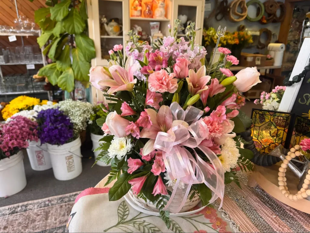 Basket arrangement featuring pink lilies, roses, and fresh greenery